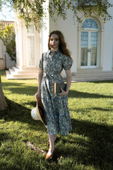 a lady in a blue floral printed dress with a belt